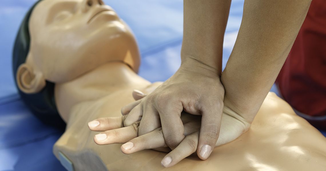 Someone training to learn CPR on a practice dummy